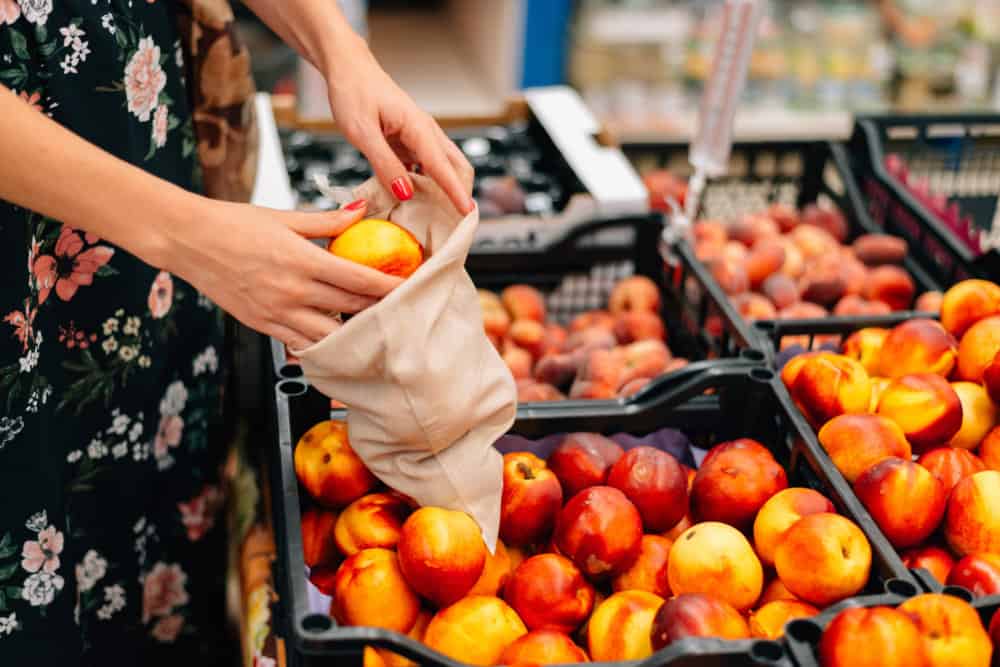 conscious consumption woman using a reusable produce bag